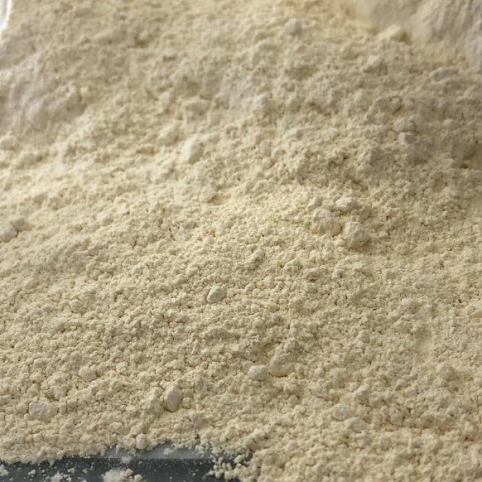Ail en poudre bio étalée, de couleur blanche à légèrement crème, avec une texture fine et homogène.